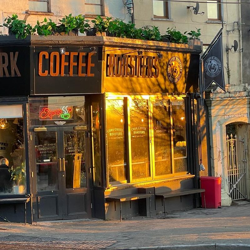 A Cork Coffee Roasters café front, with gold-lit windows.