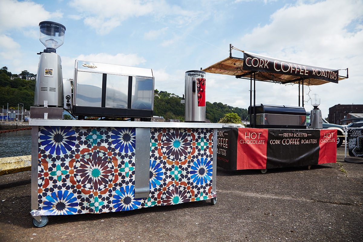 Two Cork Coffee Roasters espresso carts by the water, one with a mosaic-tile front.